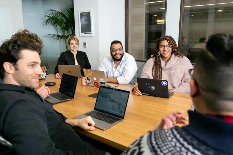 An office of coworkers sitting around a conference table, engaged in a meeting.