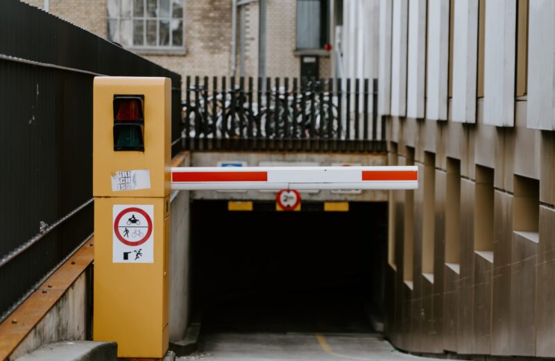 a yellow post with a red and white bar blocking the entrance to an underground car parking area