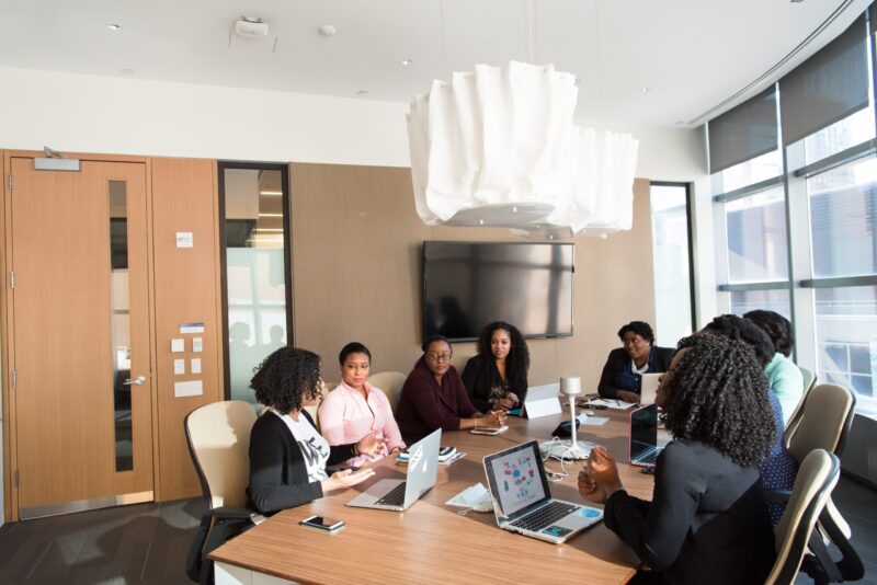 A group of women in an office, sitting around a conference table, collaborating in a meeting
